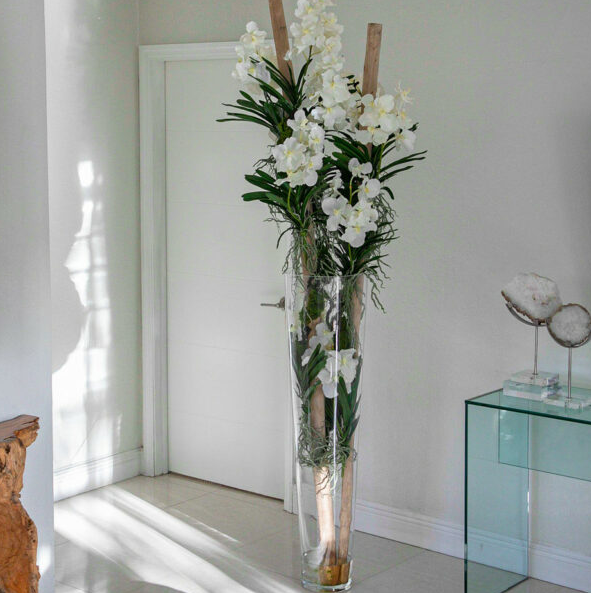 blanco vanda orquídeas y flotante madera dentro un grande cónico vidrio jarrón.